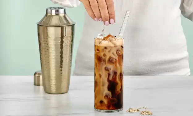 Garnishing Starbucks Brown Sugar Oat Milk Shaken Espresso with cinnamon